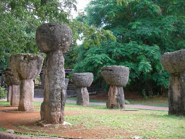 A row of ancient latte stone pillars with rounded capstones standing in a grassy clearing on Guam