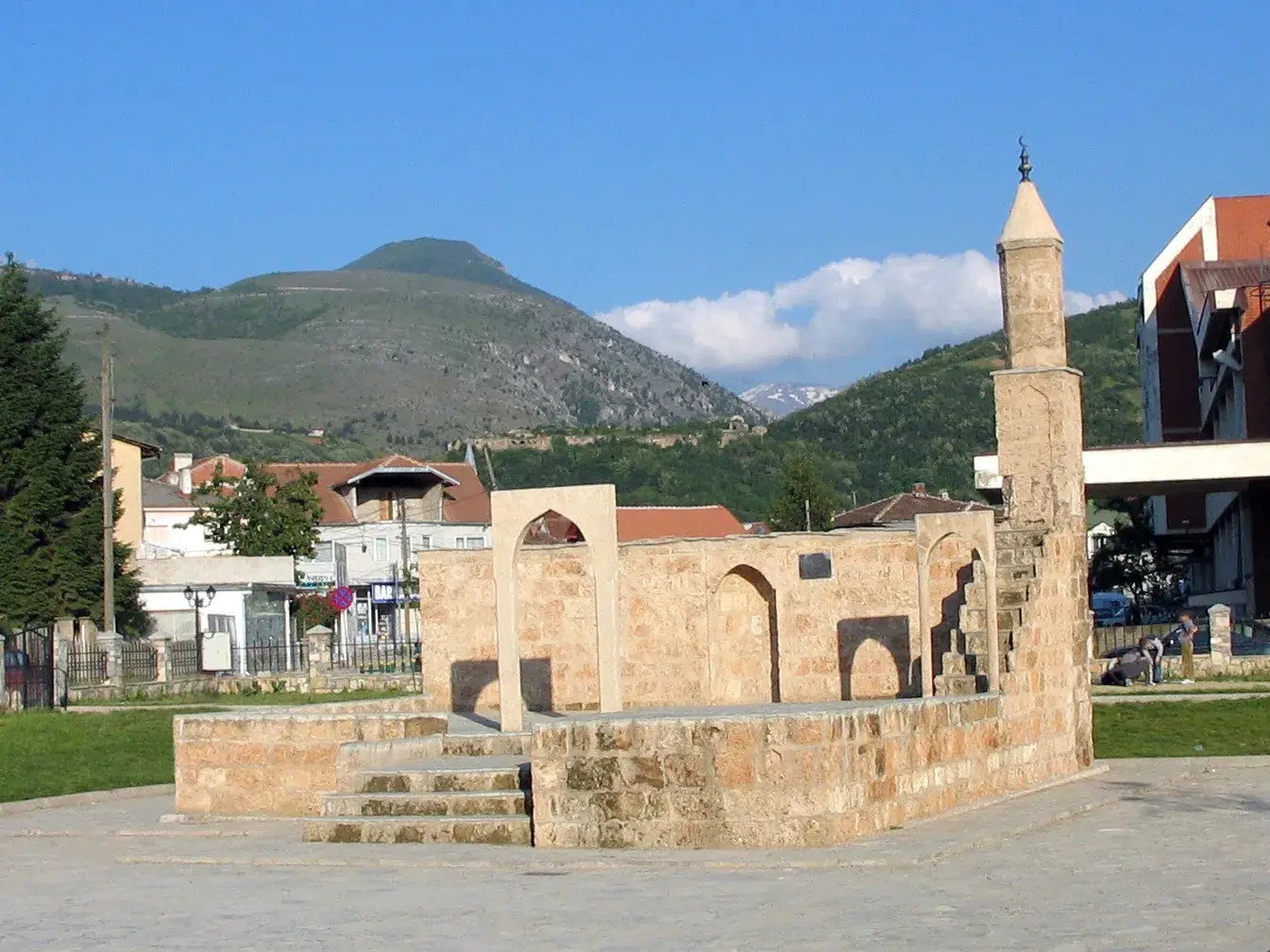 A historic Ottoman-era mosque with a slender minaret in a Balkan town square