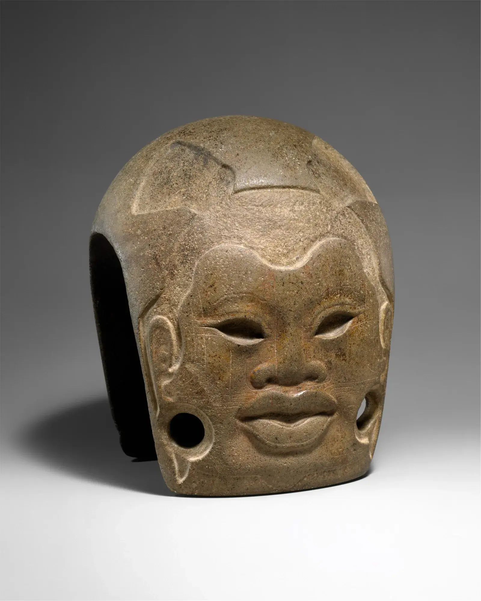 A massive Olmec colossal stone head carved with a unique face and helmet-like headdress