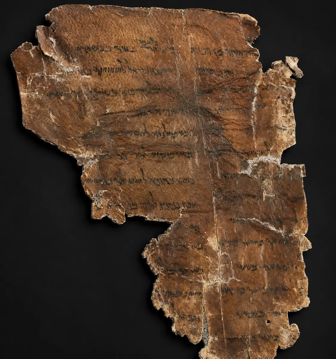 A small darkened parchment fragment ruled into columns of short repeating Hebrew entries