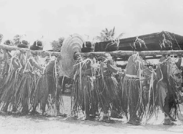A line of Yapese dancers in grass skirts and hibiscus fiber costumes performing a chanted dance at Yap Day