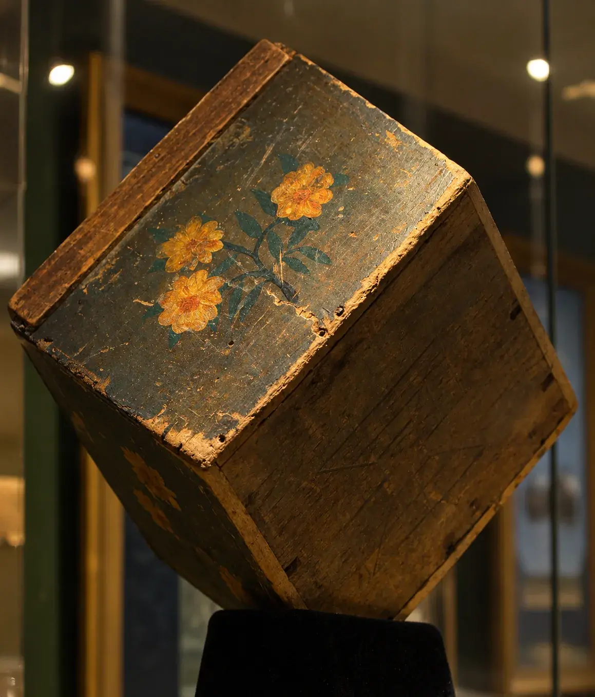 A weathered, roughly built wooden tea chest displayed as a museum artifact
